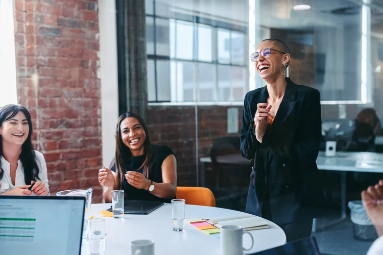 Mitarbeiterin wird von ihrem Team im Büro beglückwünscht